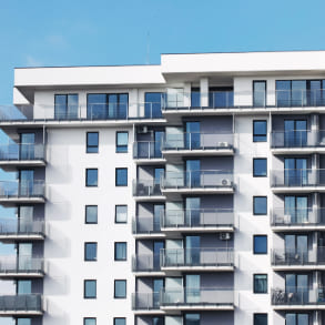 Modern apartment building with multiple floors and glass balconies, showcasing the contrast between top floor and ground floor living.